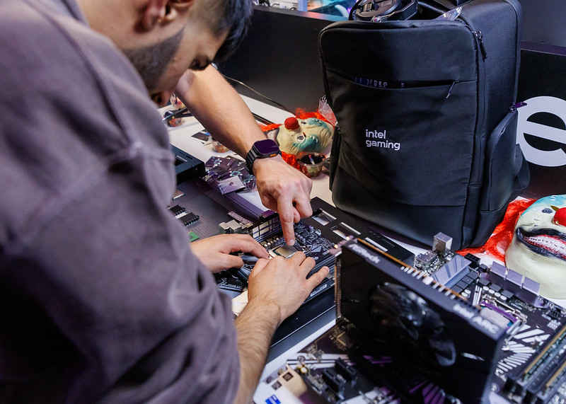 A gamer taking part in a motherboard installation challenge featuring an Intel gaming backpack in the background. 