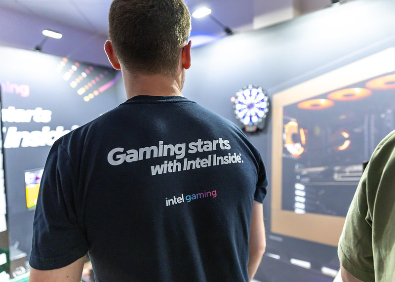 An Intel member of staff playing on a dart board wearing a t-shirt with the description of Gaming starts with Intel Inside. 